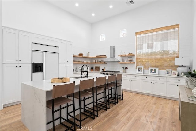 56610 Muirfield Ln, Quinta, CA 92253 - kitchen with wall chimney range hood, open shelves, paneled built in refrigerator, a high ceiling, and an island with sink