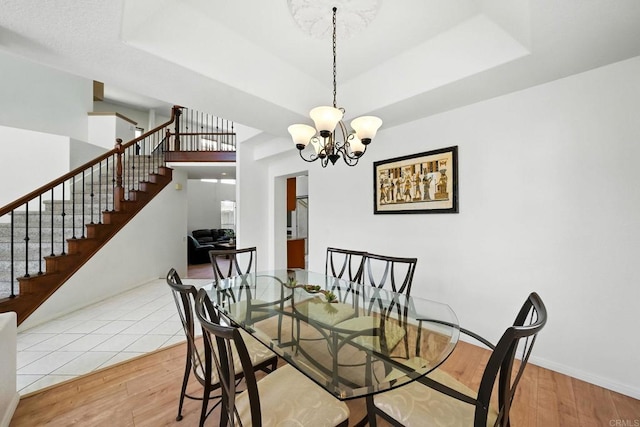 18103 Smokesignal Dr, San Diego, CA 92127 - dining area featuring stairs, wood finished floors, a chandelier, and a raised ceiling