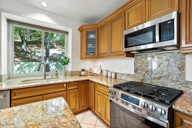 18103 Smokesignal Dr, San Diego, CA 92127 - kitchen featuring appliances with stainless steel finishes, brown cabinetry, light stone countertops, and glass insert cabinets