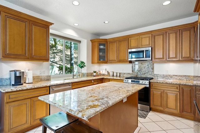 18103 Smokesignal Dr, San Diego, CA 92127 - kitchen featuring appliances with stainless steel finishes, brown cabinetry, recessed lighting, a kitchen island, and light stone countertops