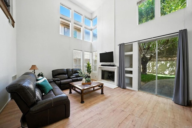 18103 Smokesignal Dr, San Diego, CA 92127 - living area with a high ceiling, wood-type flooring, plenty of natural light, and a glass covered fireplace