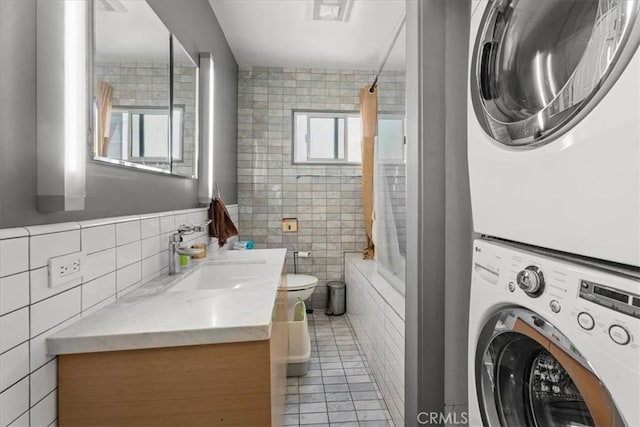 1411 N Hayworth Ave Unit 15, West Hollywood, CA 90046 - full bath with tile walls, stacked washer and clothes dryer, vanity, tiled shower / bath combo, and tile patterned flooring