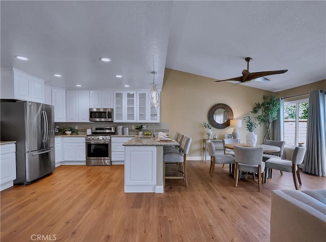 22182 Platino, Mission Viejo, CA 92691 - kitchen with stainless steel appliances, a peninsula, ceiling fan, glass insert cabinets, and white cabinets