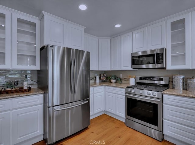 22182 Platino, Mission Viejo, CA 92691 - kitchen featuring appliances with stainless steel finishes, white cabinetry, tasteful backsplash, light wood-type flooring, and recessed lighting
