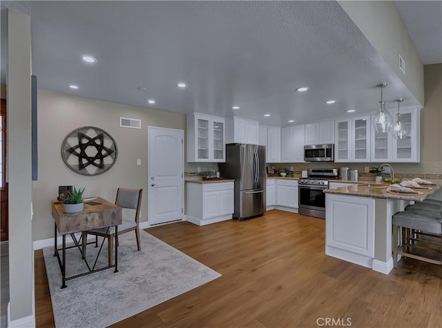 22182 Platino, Mission Viejo, CA 92691 - kitchen featuring stainless steel appliances, a peninsula, wood finished floors, white cabinets, and recessed lighting