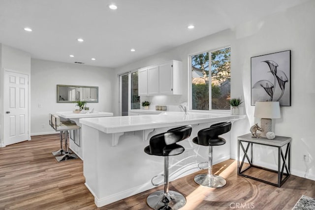 24186 Matthew Pl, Newhall, CA 91321 - kitchen with a kitchen bar, white cabinets, recessed lighting, a peninsula, and light wood-type flooring