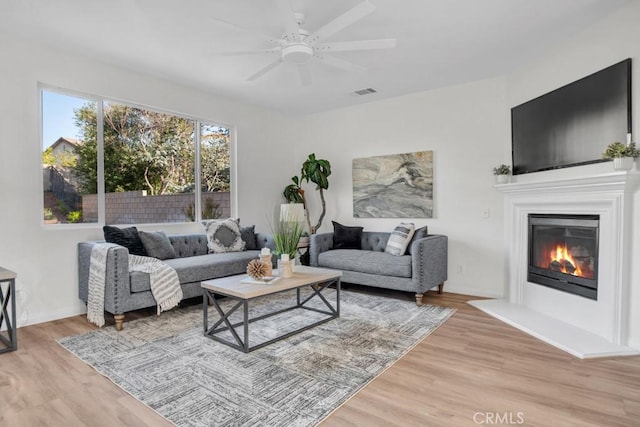 24186 Matthew Pl, Newhall, CA 91321 - living area with light wood-style flooring, a glass covered fireplace, and a ceiling fan