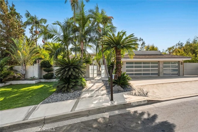 10255 Overhill Dr, Santa Ana, CA 92705 - view of property hidden behind natural elements featuring a garage, driveway, and stucco siding