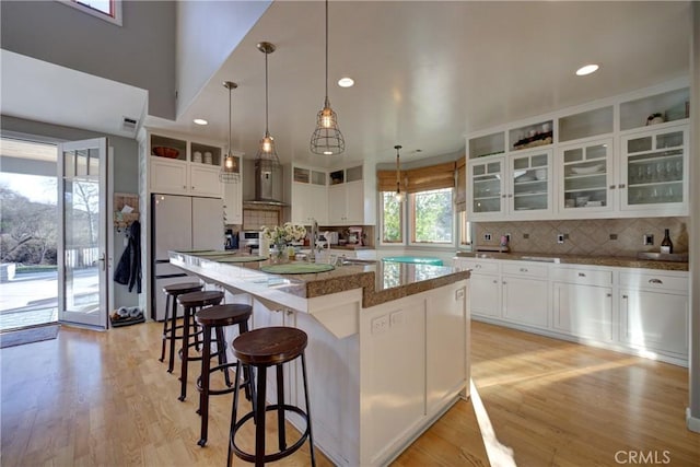 2166 Lopez Dr, Arroyo Grande, CA 93420 - kitchen with freestanding refrigerator, backsplash, a breakfast bar area, white cabinets, and light wood-style floors