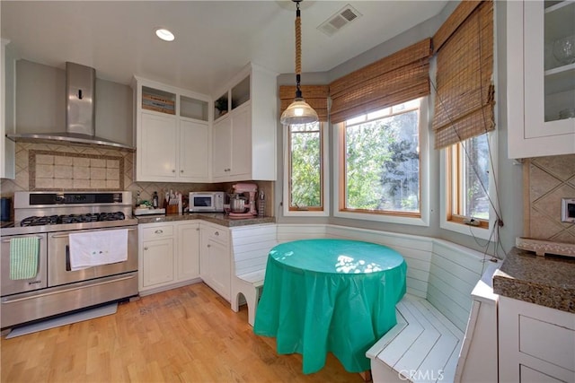 2166 Lopez Dr, Arroyo Grande, CA 93420 - kitchen with wall chimney exhaust hood, stainless steel gas range, white microwave, white cabinetry, and glass insert cabinets