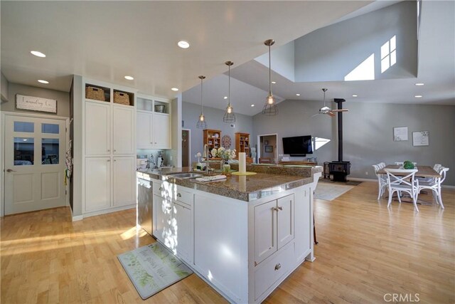 2166 Lopez Dr, Arroyo Grande, CA 93420 - kitchen with a wood stove, open floor plan, a kitchen island with sink, white cabinets, and light wood-style flooring