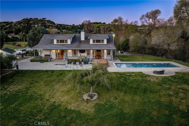 2166 Lopez Dr, Arroyo Grande, CA 93420 - back of property at dusk with a chimney, an outdoor pool, a yard, and covered porch