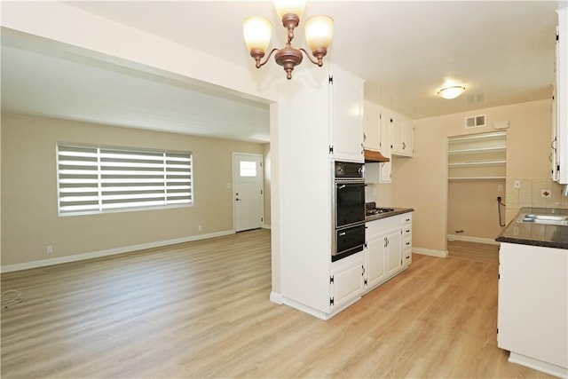 1116 N Center St, Orange, CA 92867 - kitchen with black oven, dark countertops, white cabinetry, and under cabinet range hood