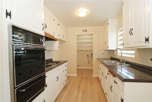 1116 N Center St, Orange, CA 92867 - kitchen with black oven, a warming drawer, dark countertops, under cabinet range hood, and white cabinets