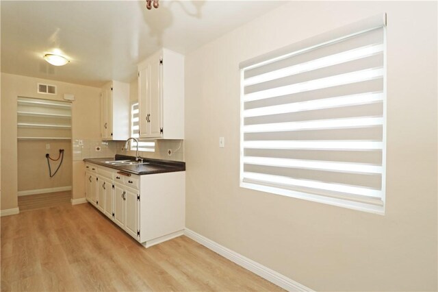 1116 N Center St, Orange, CA 92867 - kitchen with light wood finished floors, white cabinets, tasteful backsplash, and dark countertops