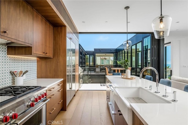 2821 Alma Ave, Manhattan Beach, CA 90266 - kitchen featuring high end stove, brown cabinetry, light countertops, backsplash, and light wood finished floors