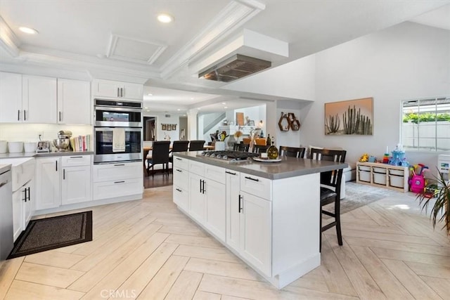 1174 Kingston St, Costa Mesa, CA 92626 - kitchen with appliances with stainless steel finishes, a breakfast bar area, white cabinets, dark countertops, and ornamental molding