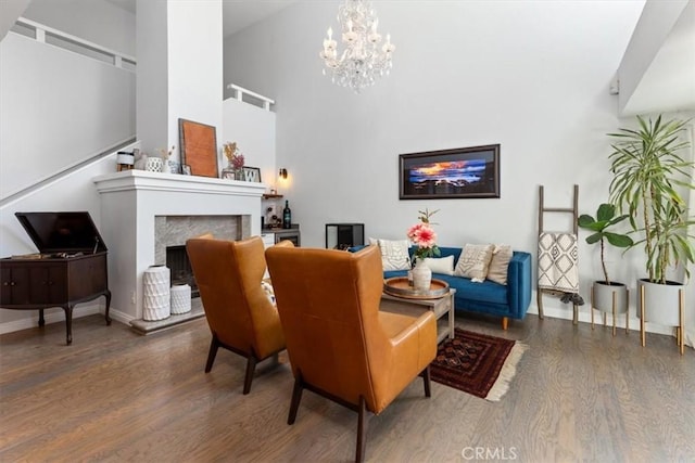 1174 Kingston St, Costa Mesa, CA 92626 - living room featuring wood finished floors, a chandelier, a fireplace with raised hearth, and a towering ceiling