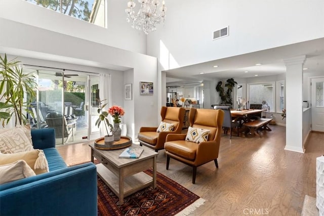 1174 Kingston St, Costa Mesa, CA 92626 - living room featuring wood finished floors, a high ceiling, ornate columns, and a chandelier