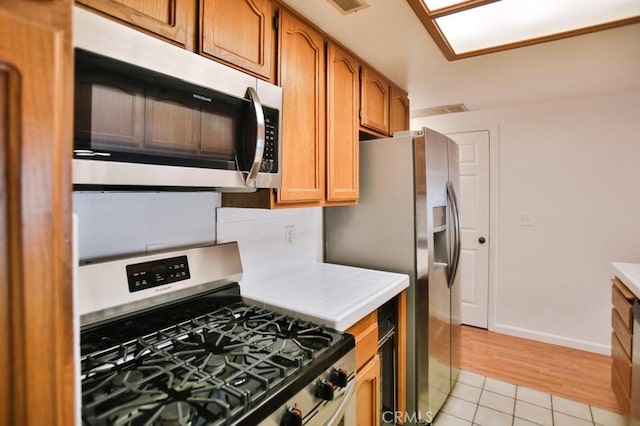 11600 Warner Ave Unit 428, Fountain Valley, CA 92708 - kitchen featuring stainless steel appliances, tile counters, light tile patterned flooring, and brown cabinets