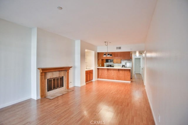 11600 Warner Ave Unit 428, Fountain Valley, CA 92708 - unfurnished living room featuring light wood-style floors and a tile fireplace
