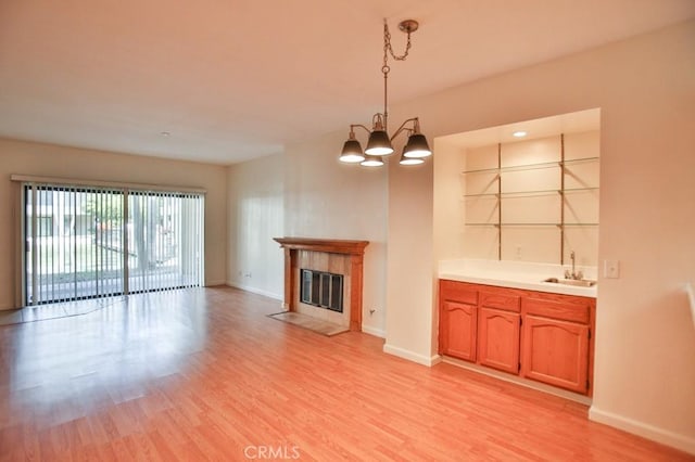 11600 Warner Ave Unit 428, Fountain Valley, CA 92708 - unfurnished living room with light wood finished floors, a tile fireplace, a chandelier, and bar with sink