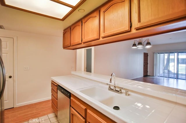 11600 Warner Ave Unit 428, Fountain Valley, CA 92708 - kitchen featuring stainless steel dishwasher, tile countertops, brown cabinets, fridge, and light wood-type flooring