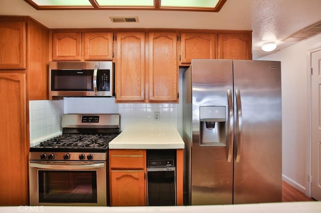 11600 Warner Ave Unit 428, Fountain Valley, CA 92708 - kitchen featuring stainless steel appliances, light countertops, decorative backsplash, and brown cabinets