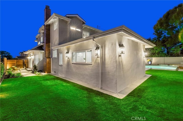 245 Surf Pl, Seal Beach, CA 90740 - back of house at twilight featuring a chimney and stucco siding