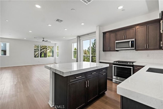 253 Steely, Irvine, CA 92614 - kitchen featuring appliances with stainless steel finishes, a kitchen island, recessed lighting, decorative backsplash, and light wood-style flooring