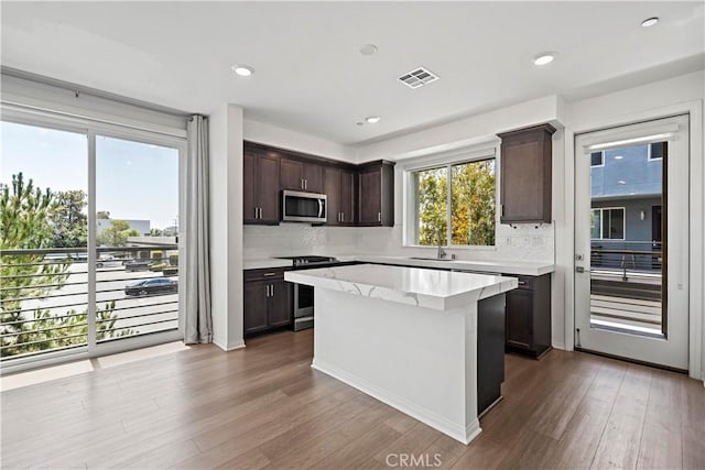 253 Steely, Irvine, CA 92614 - kitchen with appliances with stainless steel finishes, dark brown cabinets, wood finished floors, tasteful backsplash, and plenty of natural light