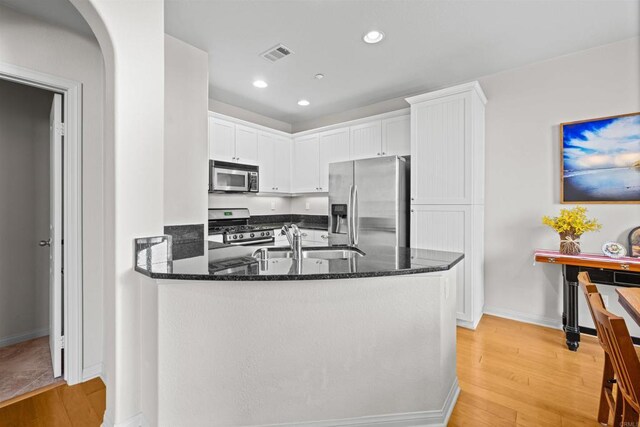 835 Harbor Cliff Way Unit 286, Oceanside, CA 92054 - kitchen featuring appliances with stainless steel finishes, light wood-style floors, dark stone countertops, white cabinets, and a peninsula