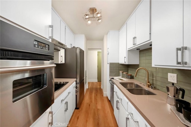 1010 Palm Ave Unit 207, West Hollywood, CA 90069 - kitchen with stainless steel appliances, white cabinets, backsplash, light wood-type flooring, and light countertops