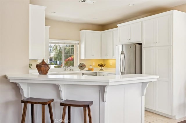 1432 Blackberry Ave, Arroyo Grande, CA 93420 - kitchen featuring freestanding refrigerator, a peninsula, white cabinetry, light countertops, and a breakfast bar