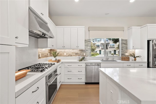 133 Denali, Lake Forest, CA 92630 - kitchen featuring stainless steel appliances, under cabinet range hood, white cabinetry, tasteful backsplash, and light wood finished floors