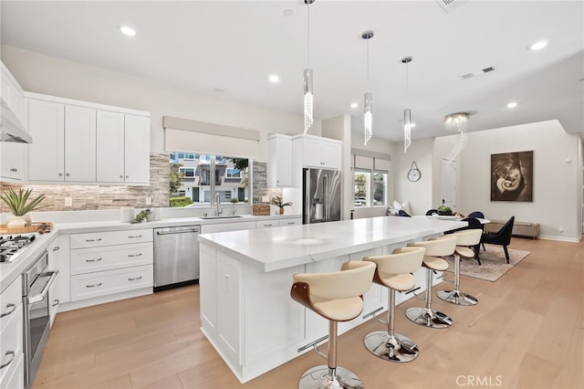 133 Denali, Lake Forest, CA 92630 - kitchen featuring appliances with stainless steel finishes, backsplash, a kitchen breakfast bar, light wood-style flooring, and a kitchen island