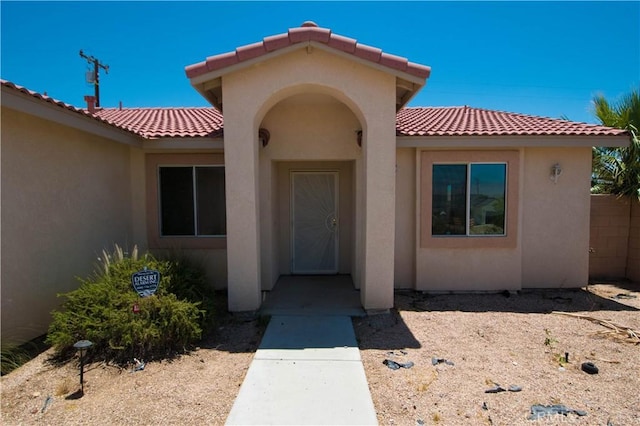 9464 Palm Dr, Desert Hot Springs, CA 92240 - view of exterior entry with a tile roof and stucco siding