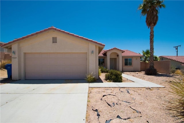 9464 Palm Dr, Desert Hot Springs, CA 92240 - mediterranean / spanish-style house with stucco siding, a tiled roof, an attached garage, and concrete driveway