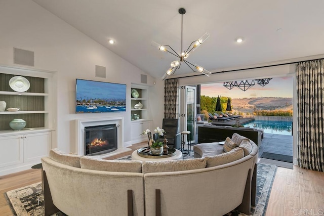 15614 S Chevy Chase, San Diego, CA 92127 - living area with built in shelves, wood finished floors, a glass covered fireplace, a chandelier, and high vaulted ceiling