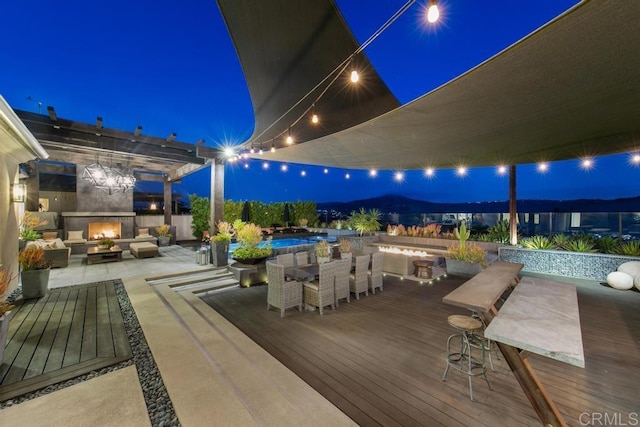 15614 S Chevy Chase, San Diego, CA 92127 - patio at twilight with outdoor dining space, a wooden deck, an outdoor living space with a fireplace, a swimming pool, and a patio area