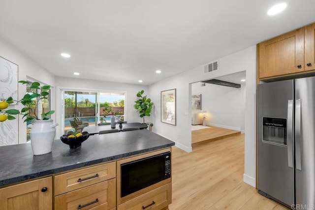 10437 Hermanos Rd, San Diego, CA 92124 - kitchen with stainless steel fridge, black microwave, light wood-style flooring, dark countertops, and recessed lighting
