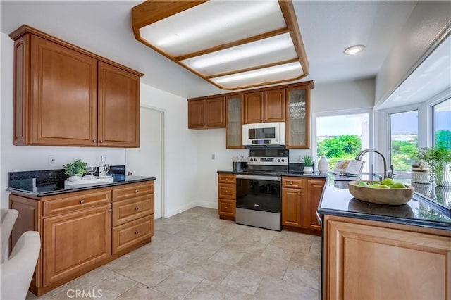 24482 Chrisanta Dr, Mission Viejo, CA 92691 - kitchen featuring stainless steel range with electric stovetop, white microwave, dark countertops, and brown cabinetry