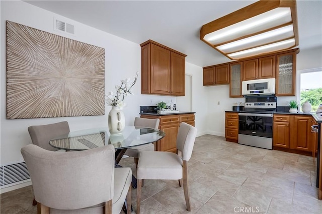 24482 Chrisanta Dr, Mission Viejo, CA 92691 - kitchen featuring stainless steel range with electric cooktop, white microwave, dark countertops, and brown cabinetry
