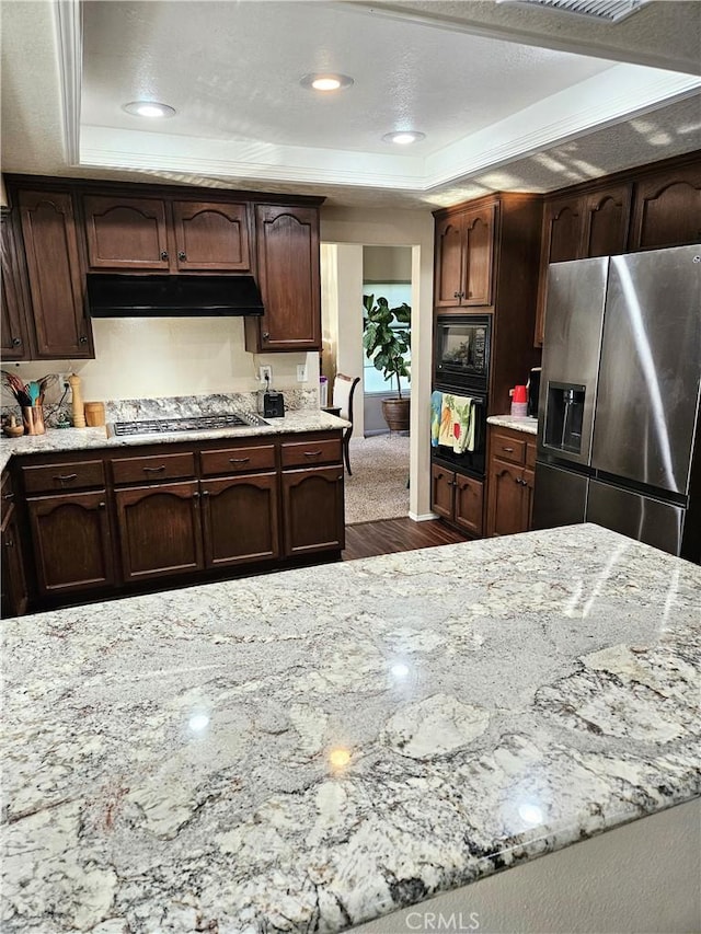10771 Orchard View Ln, Riverside, CA 92503 - kitchen with black appliances, a raised ceiling, under cabinet range hood, dark wood-type flooring, and light stone counters