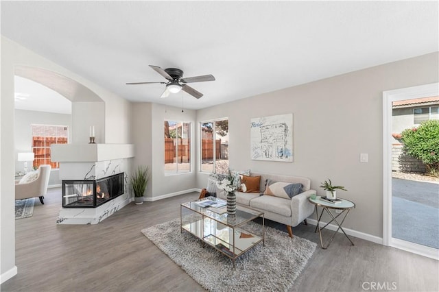 37921 Tackstem St, Palmdale, CA 93552 - living room featuring wood finished floors, a ceiling fan, a multi sided fireplace, and arched walkways