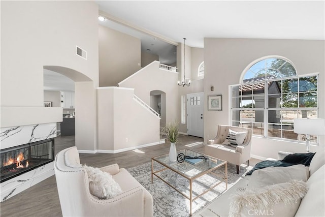 37921 Tackstem St, Palmdale, CA 93552 - living room with arched walkways, high vaulted ceiling, wood finished floors, a high end fireplace, and a chandelier