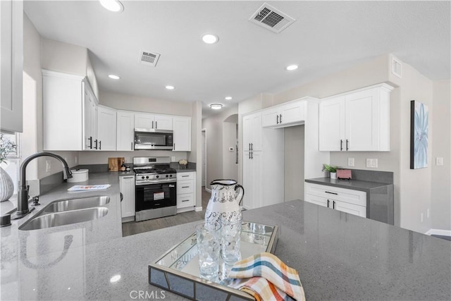37921 Tackstem St, Palmdale, CA 93552 - kitchen featuring stainless steel appliances, dark stone countertops, white cabinetry, recessed lighting, and arched walkways