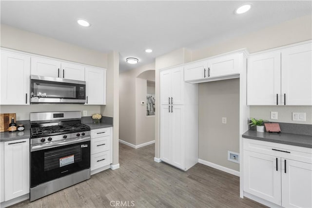 37921 Tackstem St, Palmdale, CA 93552 - kitchen featuring appliances with stainless steel finishes, dark countertops, arched walkways, white cabinets, and recessed lighting