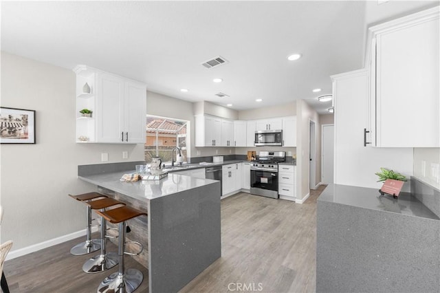 37921 Tackstem St, Palmdale, CA 93552 - kitchen with stainless steel appliances, light wood-style flooring, a peninsula, white cabinets, and open shelves