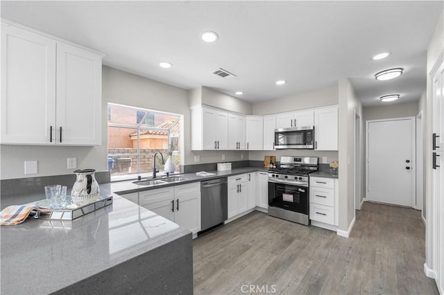37921 Tackstem St, Palmdale, CA 93552 - kitchen with stainless steel appliances, light wood-style flooring, white cabinetry, dark stone counters, and recessed lighting